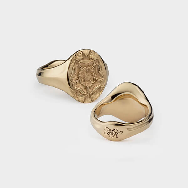 A yellow gold oval signet ring with a bespoke seal engraving of a tudor rose.